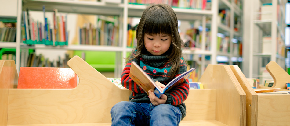 Toddler reading a book at home