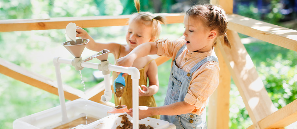 Two young girls learn about gardening while playing in soil at a Montessori school in Austin