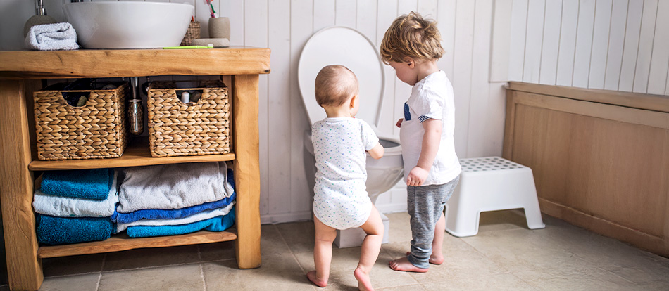 older child gives a bathroom tour to the younger child during potty training