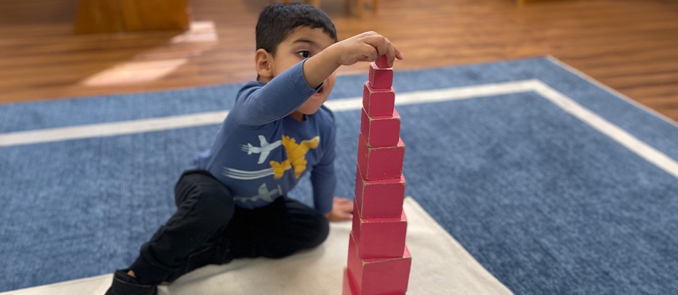 Montessori preschool student stacks blocks to make a tower