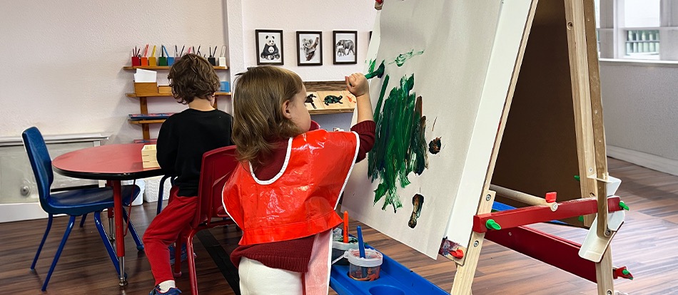 a Montessori preschool student paints in the classroom
