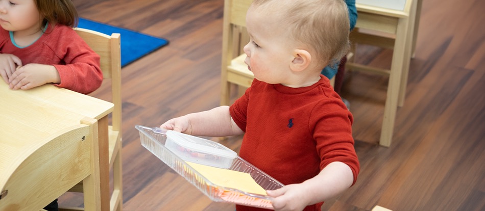 montessori preschooler learns how to clean up his space in the classroom